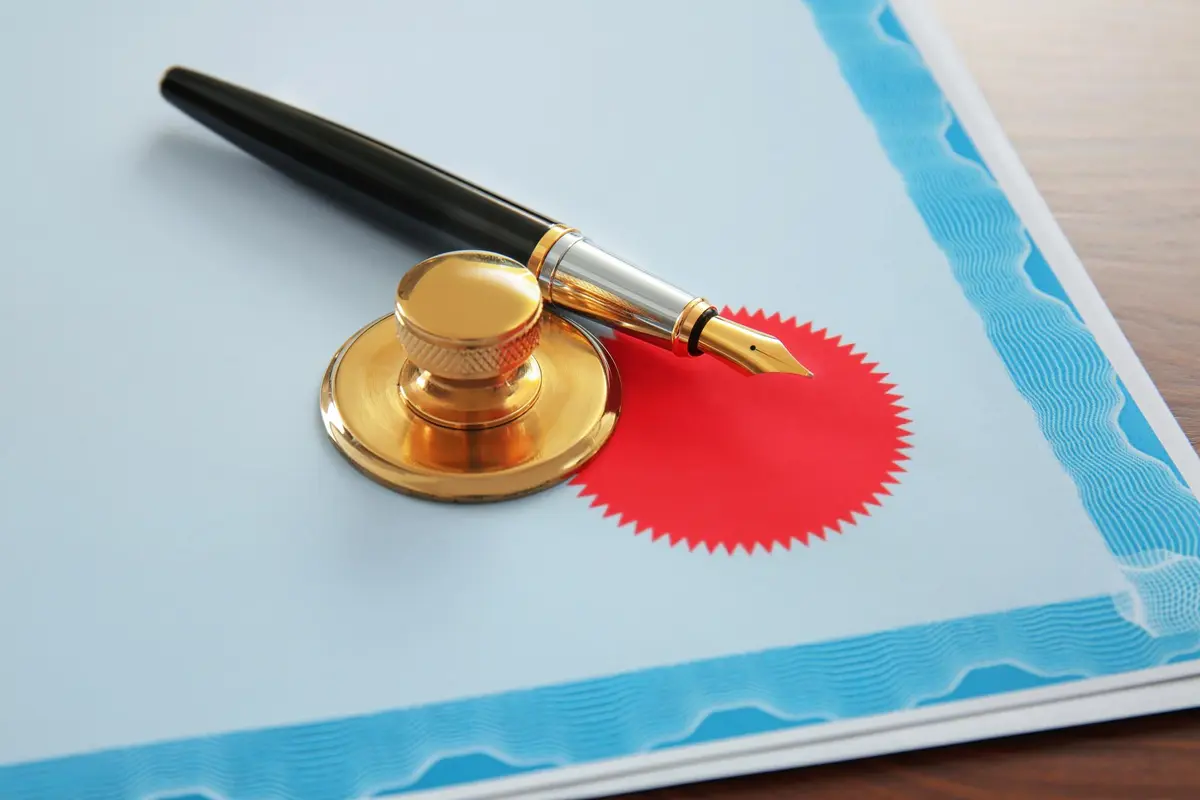Gouden zegel en vulpen op blauw certificaat voor apostille